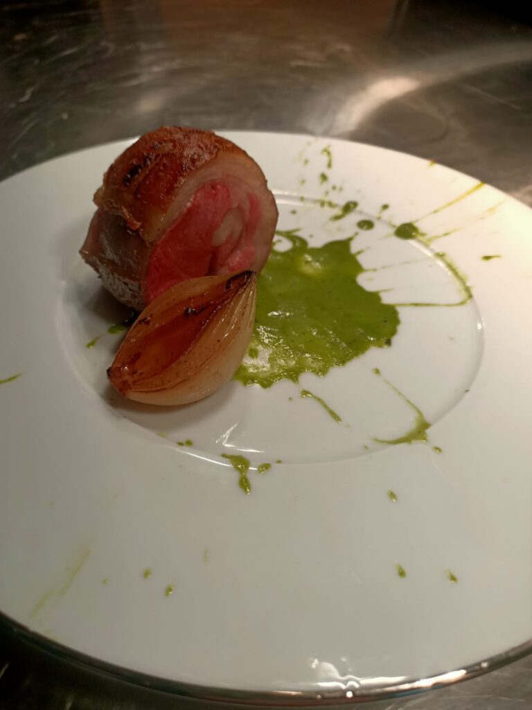 Steak cut plated with a green sauce splatter